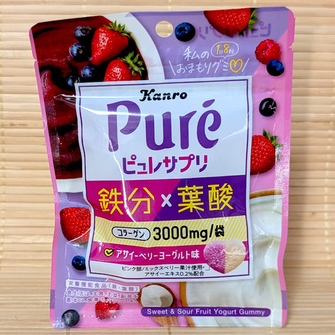 A pink and purple 56g pouch of Kanro Puré Suppli Berry Yogurt gummies showing acai berries, strawberries, yogurt, and a two-tone heart gummy on a bamboo mat background.