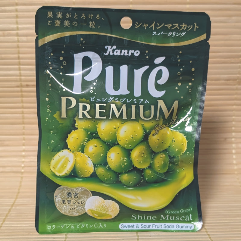 A dark green resealable pouch of Kanro Pure Premium gummies featuring bright Shine Muscat grapes and a cross-section of the jelly center.