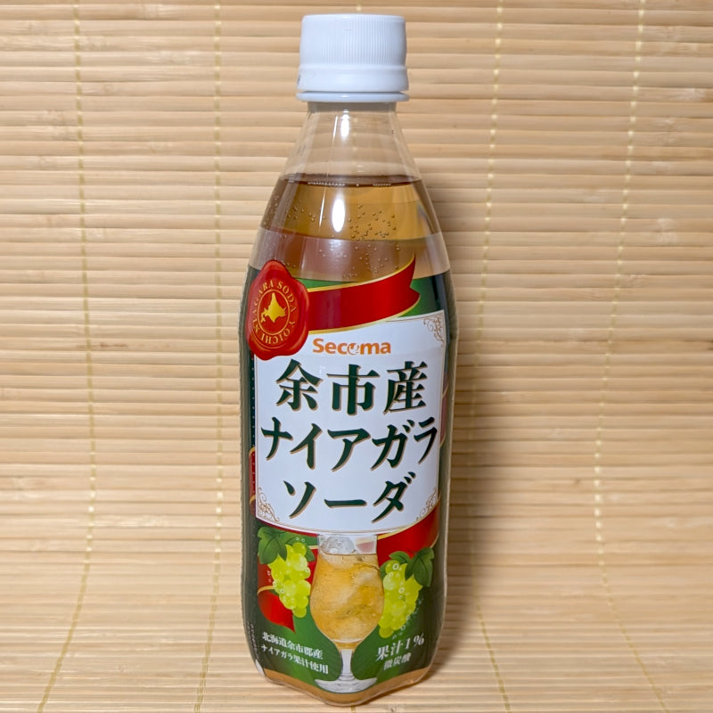 A bottle of Seicoma Yoichi Niagara Grape Soda with green grape graphics, resting on a bamboo mat.