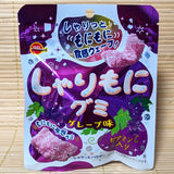 A purple 57g pouch of Bourbon Sharimoni Grape Gummies showing crunchy sugar coated gummies on a bamboo mat background.