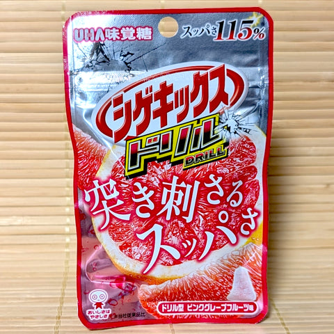 A metallic silver and red 23g pouch of Shigekix Drill Pink Grapefruit gummies featuring intense citrus graphics on a bamboo mat.