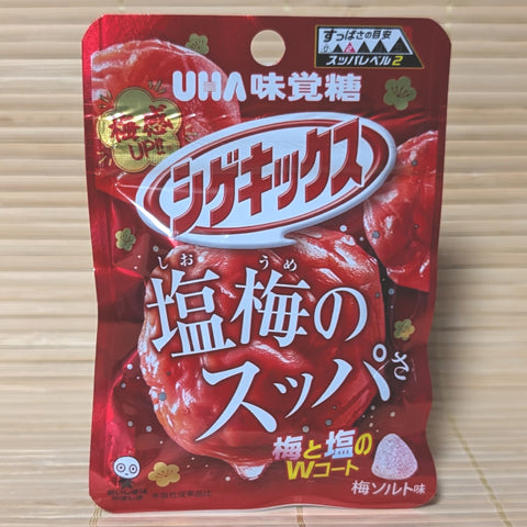 A metallic red 20g pouch of UHA Shigekix Salty Sour Ume Plum gummies showing a Level 2 sourness meter, pickled ume illustrations, and a cone-shaped gummy on a bamboo mat background.