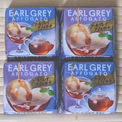 Four square mini cubes of Tirol Earl Grey Affogato chocolate featuring illustrations of tea affogato desserts and teapots on a tatami background.