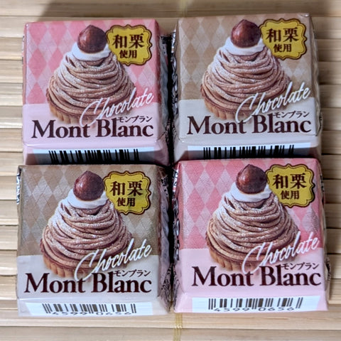 A set of four individually wrapped Tirol Mont Blanc Chestnut chocolates featuring pink and beige wrapper designs on a bamboo mat background.