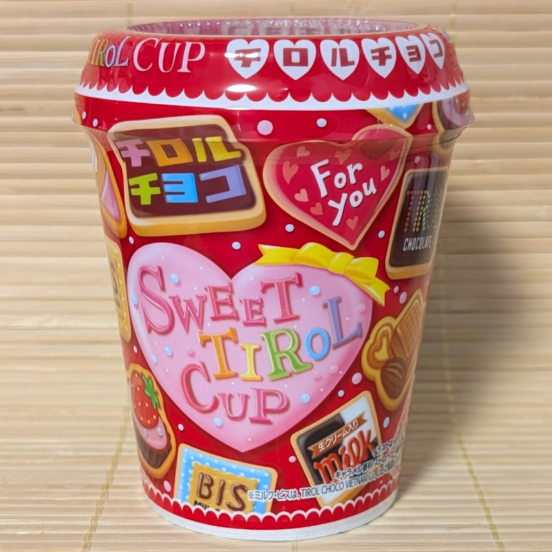 A colorful red, Valentines Day themed, Styrofoam cup of Tirol Chocolates of mixed flavors. Displayed on a tatami background.
