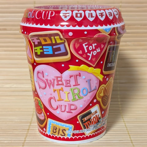 A colorful red, Valentines Day themed, Styrofoam cup of Tirol Chocolates of mixed flavors. Displayed on a tatami background.