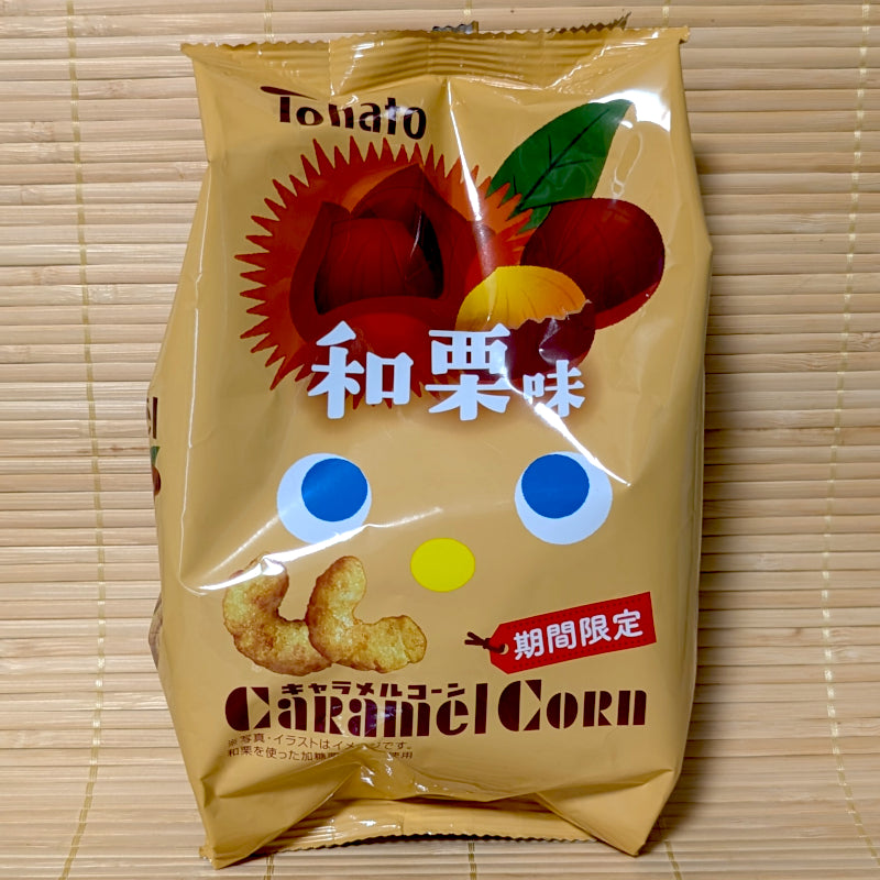 A warm golden-beige bag of Tohato Caramel Corn Waguri Chestnut featuring cute character eyes and chestnut artwork on a bamboo mat background.