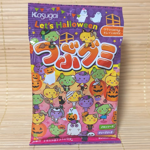 A colorful purple 70g bag of Kasugai Tsubugumi Halloween Soda Mix gummies with cute character illustrations on a bamboo mat.