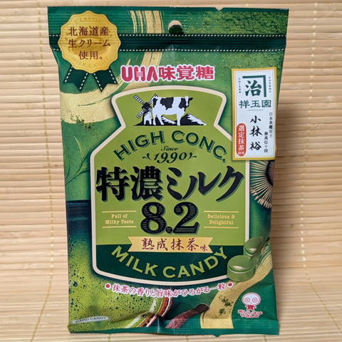 A green and gold bag of UHA Tokunou Milk 8.2 Ripe Matcha candy featuring a windmill and a cow illustration.