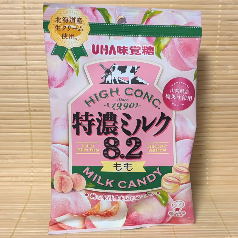 A pink and green bag of UHA Tokunou Milk 8.2 candy featuring illustrations of fresh peaches and a Hokkaido dairy windmill.