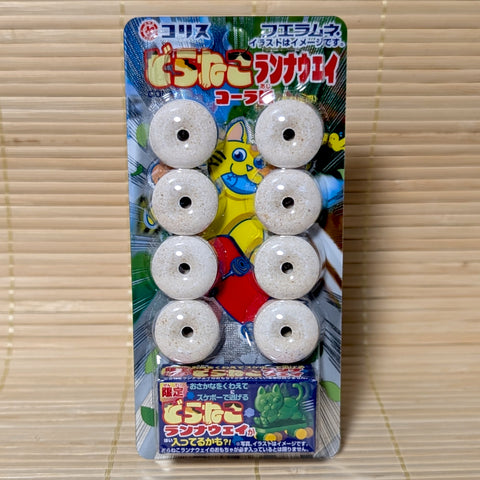 A blister pack of 8 beige whistle candies with a blue box containing a mystery Doraneko toy featuring a skateboarding cat.